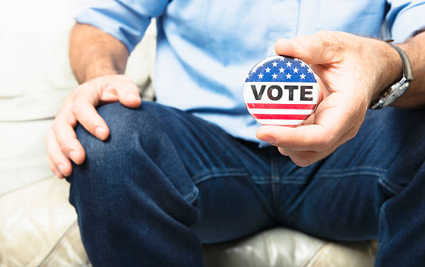 casual hombre que agarra un botón de voto para la elección - presidential election 2012 election photography fotografías e imágenes de stock