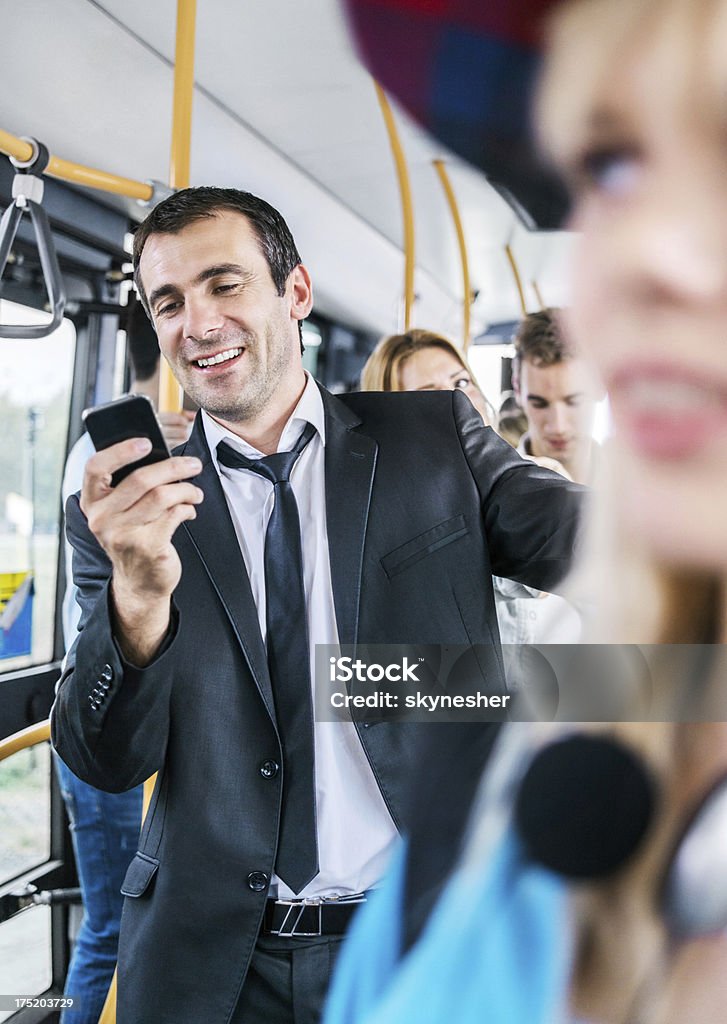 Uomo di mezza età invio di messaggi di testo, mentre per il pendolarismo in autobus. - Foto stock royalty-free di Adulto