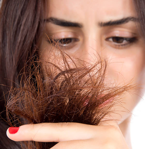 Brunette woman frowning at split ends