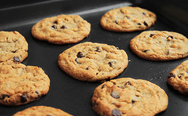 Homemade Chocolate Chip Cookies on the Pan "Still wam from the oven, a batch of home-made chocolate chip cookies. Lots of rich detail." polytetrafluoroethylene photos stock pictures, royalty-free photos & images
