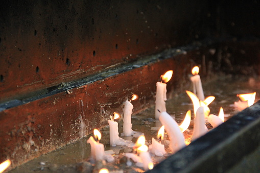 Some candles are melting and people are praying devoutly.
