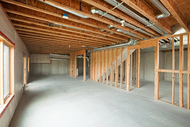 Unfinished House Walk-out Basement "An unfinished walk-out basement in a large two-story or ranch house. Basements are often left looking like this after initial construction, a cost saving move which allows for future expansion. This image would make a good starting point for a remodeling or house completion concept. The floor and right exterior wall are poured concrete, the left wall is framed, insulated and covered with plastic. The floor joists are engineered I-beams. Some broken concrete is visible behind the far wood frame wall." undone stock pictures, royalty-free photos & images