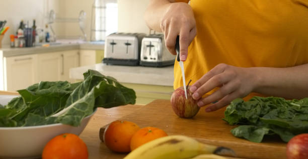istock Kitchen, table and hands cutting fruit and vegetables for cooking a recipe or healthy food. Woman, chopping and prepare apple with knife on counter in home for nutrition, supplement or protein shake 1752055962