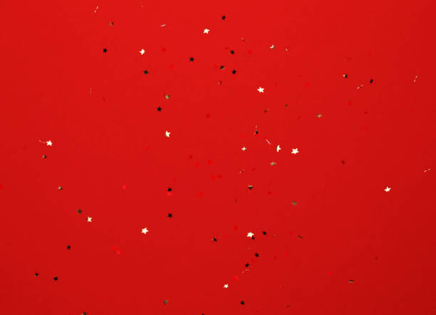 istock Star Shaped Gold Colored Confetti Falling over Red Background 1752057088