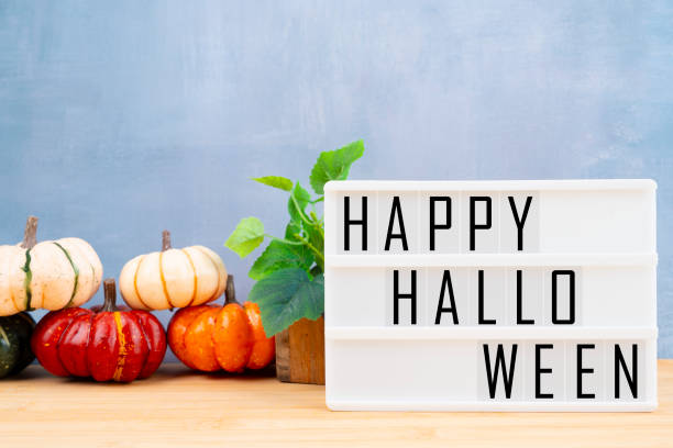 Lightbox with message HAPPY HALLOWEEN framed and pumpkins with green leaves on blue background