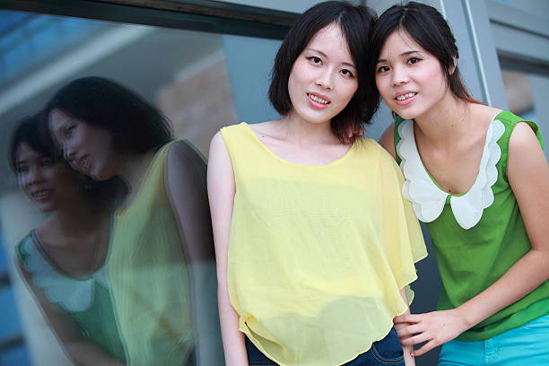 Two girls leaning against the glass wall of the office building