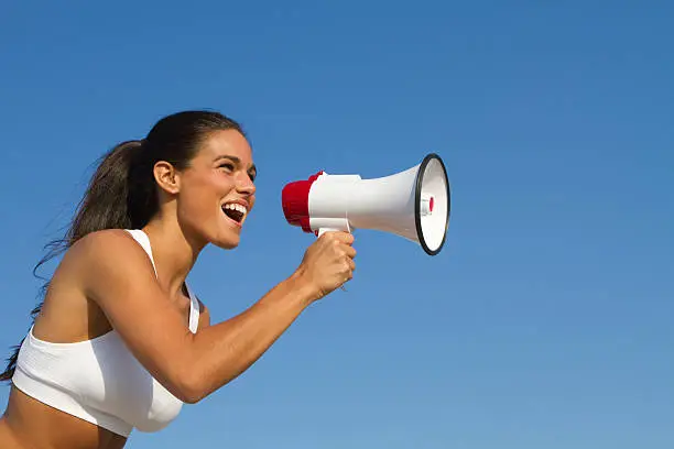 fit woman making announcement on megaphone with blue sky copy space