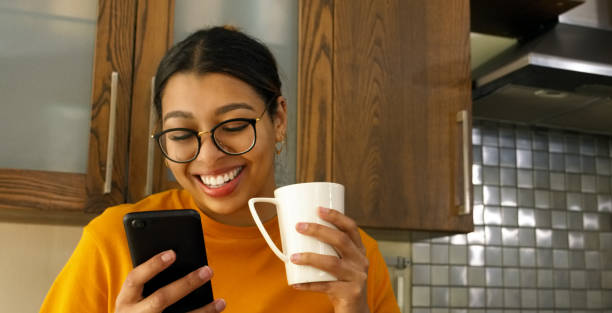 istock Woman, coffee and phone with reading, kitchen and texting for web blog, chat and email notification in home. Girl, smartphone and click for mobile app, social network or drink with tea cup in house 1752068397