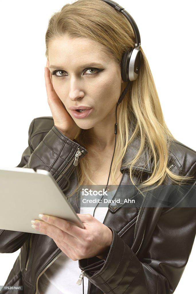 Beautiful woman listening to music from a digital tablet Beautiful woman in leather jacket listening to music from a digital tablet. High Key. Copy space. Technical Details: Nikon D800. ISO 100. 20-29 Years Stock Photo