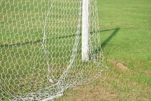 netting of football goal frame on stadium field in sunny day