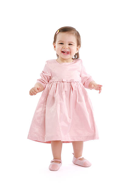 Cute little girl standing and playfully smiling to camera.
