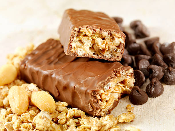 Granola Bars Chocolate Dipped Granola Bars with Peanuts and Chocolate Chips on an old Wood Table -Photographed on Hasselblad H3D2-39mb Camera Chocolate Dipped stock pictures, royalty-free photos & images