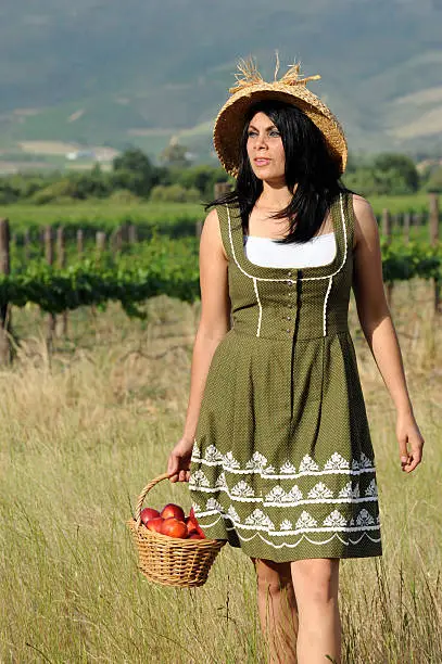 "A beautiful farmgirl with her basket of peaches and vineyards behind, on a Boland fruit farm."