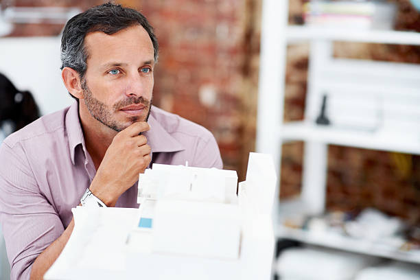 istock Man gazing at an architectural model in his office 175210148