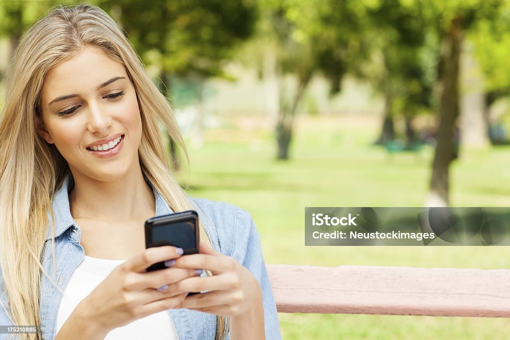 Jovem mulher usando telefone celular no parque. - Foto de stock de 20 Anos royalty-free