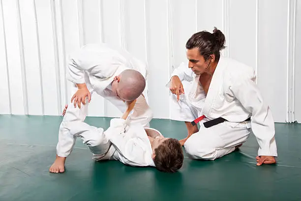 Jiu-Jitsu class - Instructor (20s) teaching students (8 and 9 years) Open Guard position.  Brazilian jiu-jitsu is a martial art, self defense system and combat sport.