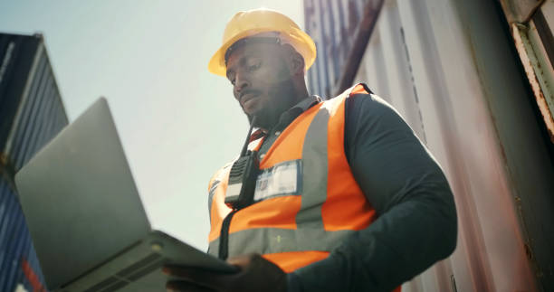 istock Man, computer and outdoor warehouse for container, cargo or freight management and e commerce website. Industrial African person with laptop for supply chain, online shipping information or logistics 1752116963