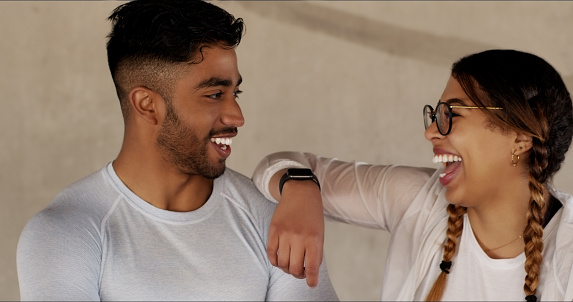 Happy, couple and on a wall together for fitness, love or training and break from a workout. Laughing, joke and a young athlete man and woman with a smile and conversation after exercise or sports