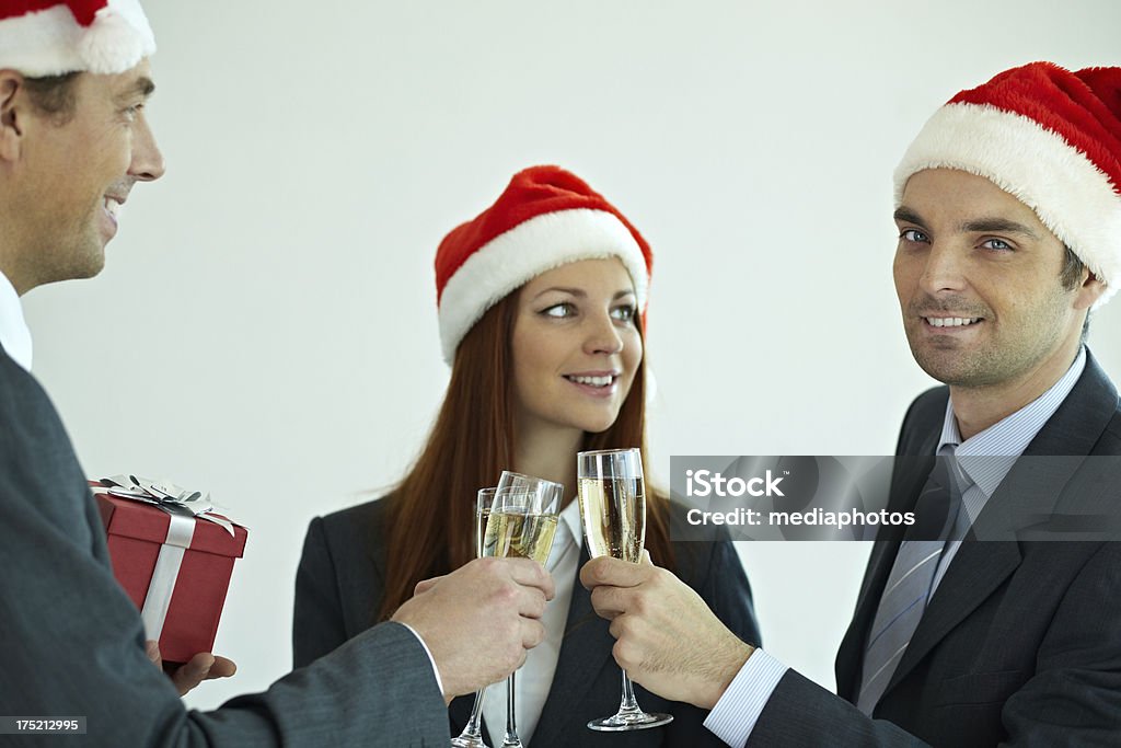 Christmas toast Business people in Santa hats celebrating Christmas with champagne Gift Stock Photo