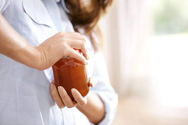 The lid is really tight! Cropped image of a woman trying to open a jar in the kitchen jar stock pictures, royalty-free photos & images