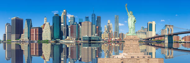 Statue of Liberty and New York City Skyline with Skyscrapers of Manhattan Financial District, World Trade Center, Brooklyn Bridge, East River and Blue Sky in the Morning. Stitched Panorama of Statue of Liberty and Manhattan Lower East Side Financial District, Brooklyn Bridge, World Trade Center and Blue Sky with Clouds Reflected in Water of East River, New York, USA. Canon EOS 6D (Full Frame censor) DSLR and Canon EF 24-105mm f/4L lens. 3:1 Image Aspect Ratio. stitched image stock pictures, royalty-free photos & images