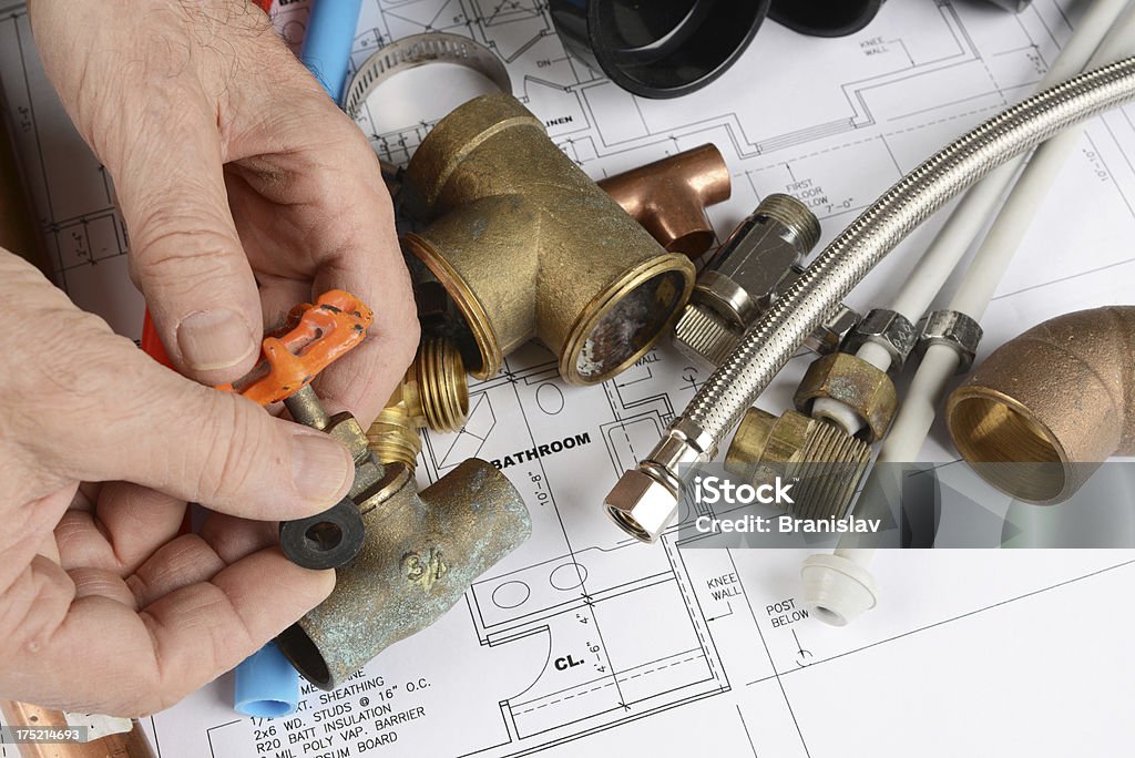 plumbing plumber holding rubber washer and bras valve over house blueprint Architecture Stock Photo