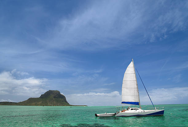 catamaran Catamaran in front of Le Morne, Mauritius.  catamaran sailing stock pictures, royalty-free photos & images