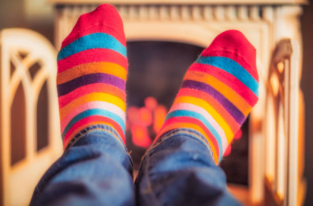 Close-up of a man's feet in stripey socks, as he keeps them warm by the fire.