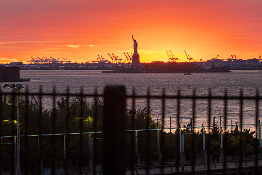 The sun sets behind the Statue of Liberty, shot from Brooklyn, NY