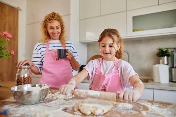 istock Mother and daughter kneading cookie dough with rolling pin at home 1752178075