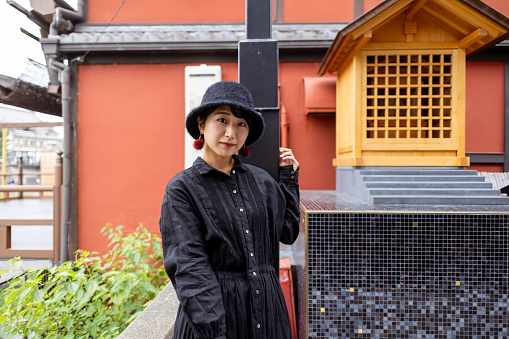 Portrait of young tourist in black dress with a hat in traditional Japanese town