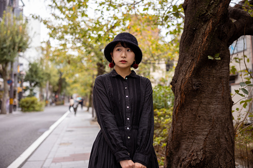 Young woman in black dress with a hat walking in traditional Japanese town