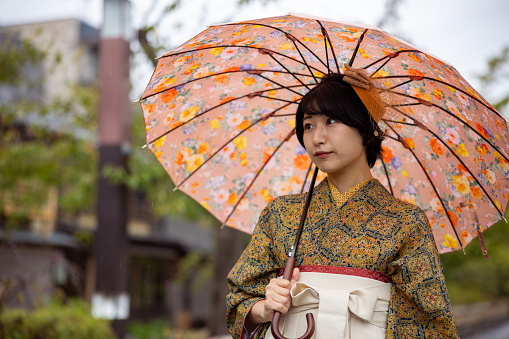Young woman in Kimono/Hakama walking in town in a rainy day