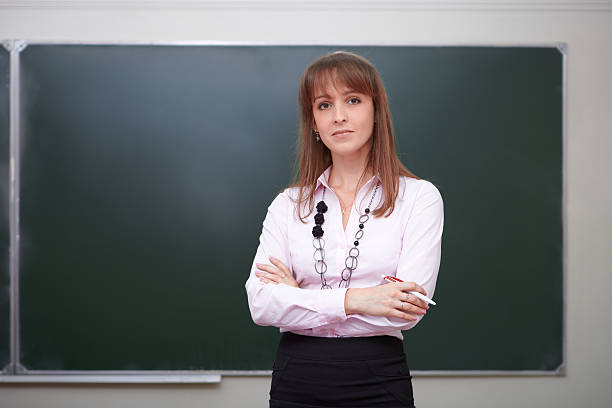 istock Teacher with pen in front of chalkboard. 175218803