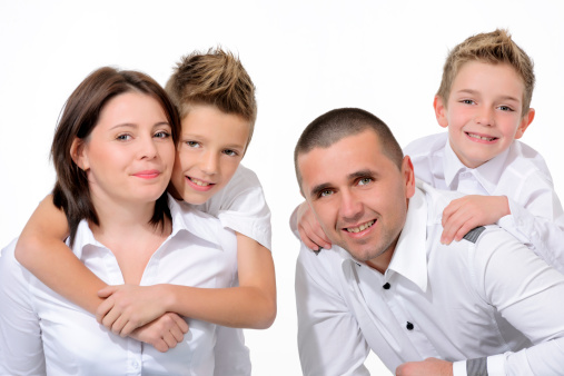 young family with two boys posing on white background.