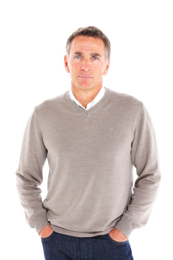 Portrait of handsome mature man standing with his hands in pocket on white background