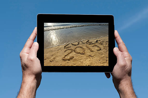 ręce z cyfrowego tabletu, blue sky - 2013 beach sand new years eve zdjęcia i obrazy z banku zdjęć