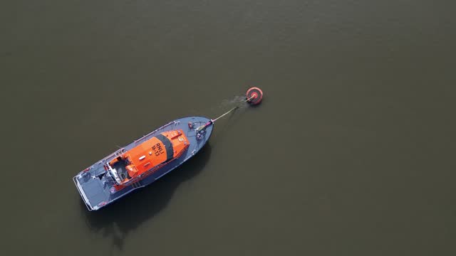 Orange UK Lifeboat mooring in brown sea waters aerial top down