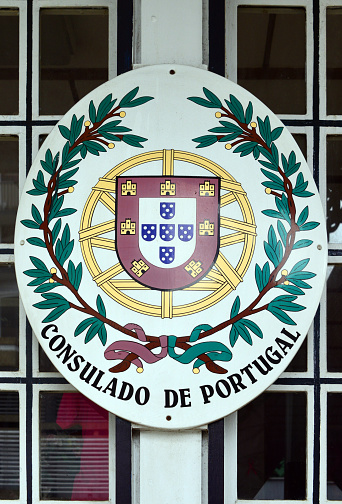 Paramaribo, Suriname: enamel sign of the Consulate of Portugal - Portuguese coat of arms - shield with seven castles, five escutcheons ('quinas') with bezants, over armillary sphere, framed by laurel branches tied with ribbons.