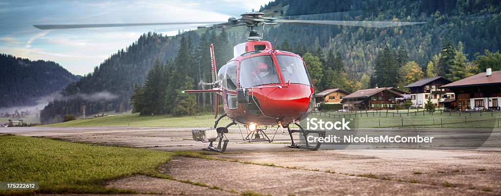 Red Helicopter about to take off in Switzerland Alps Red Helicopter about to take off in Switzerland Alps. The helix is moving. Shot at dawn.A selection of related photographs: Air Vehicle Stock Photo