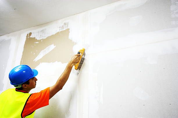 istock Decorator wearing blue hat and yellow jacket plastering wall 175222859