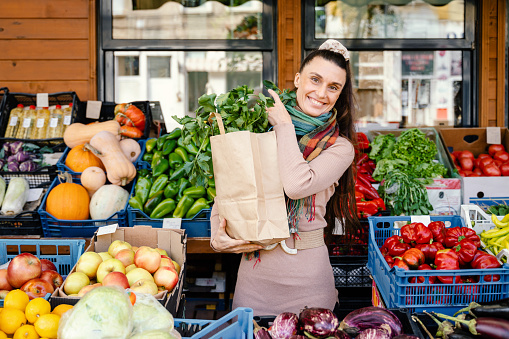 Portrait of a happy woman with a paper bag of groceries in market