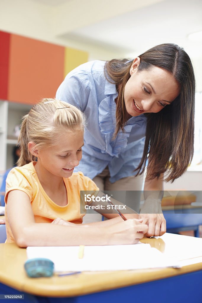 You're on the right track A beautiful young teacher helping a student with her schoolwork Adult Stock Photo