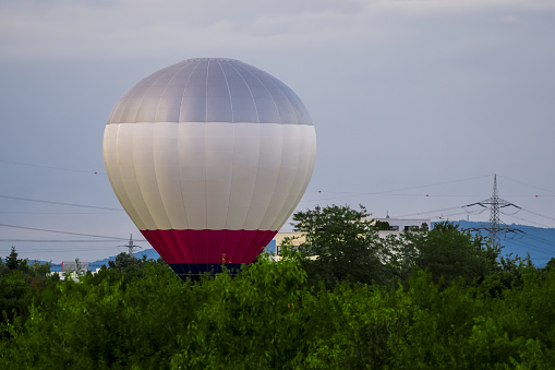 Hot air balloon landing in the middle of thicket, power lines and hills in background