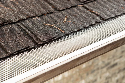 A house rain gutter with a leaf and debris shield installed to prevent leaves from clogging the gutter and eliminate annual cleaning.