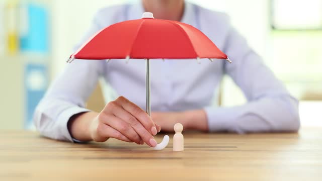 Woman holding big red umbrella above wooden figure in office