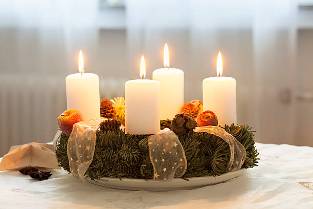 Advent wreath with 4 burning candles on table Advent wreath, 4 candles burning at the last sunday in Advent advent candle wreath adventskranz stock pictures, royalty-free photos & images