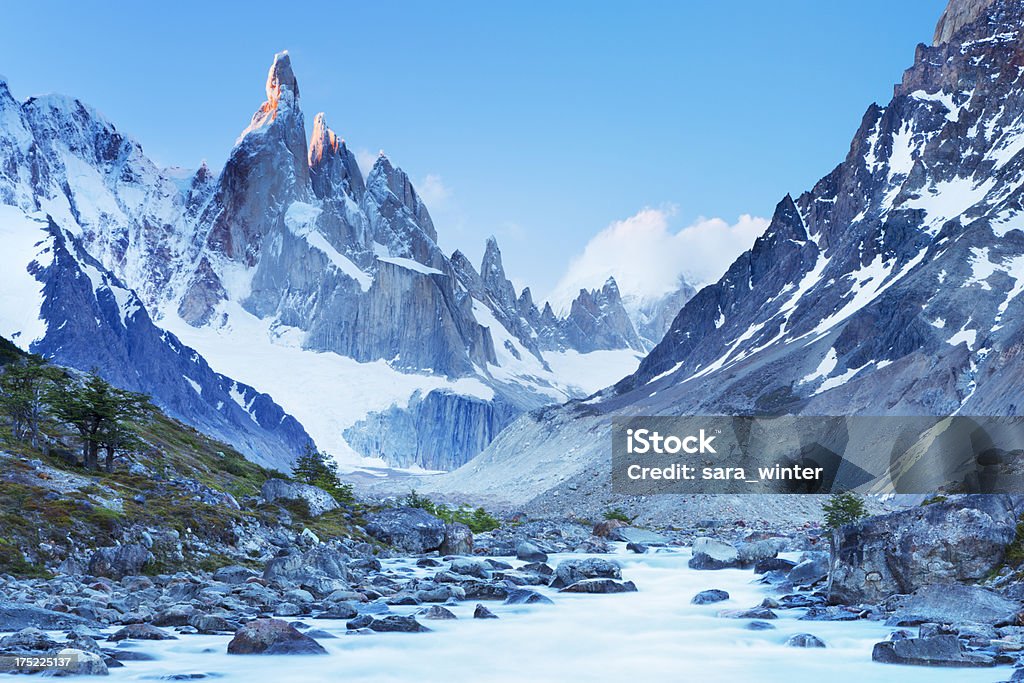 Mountain peaks of Cerro Torre, Patagonia, Argentina at sunset Last light on the peaks of Cerro Torre with a raging river below. Los Glaciares National Park Stock Photo