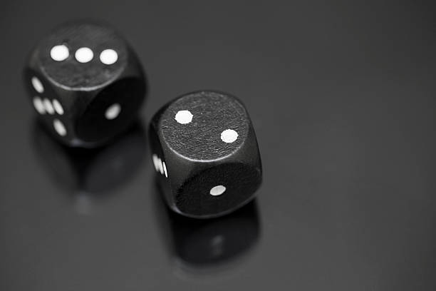Two black dices on a black reflective surface 