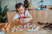 Smiling girl making Christmas cookies at home